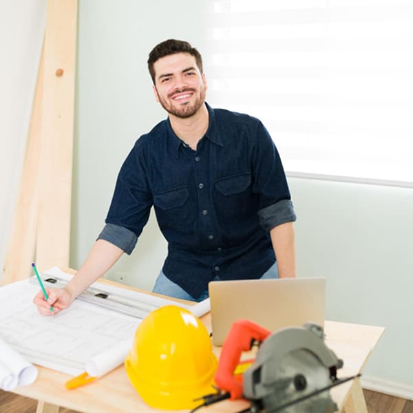 Entrepreneur en rénovation à Montréal travaillant sur des plans avec outils et ordinateur